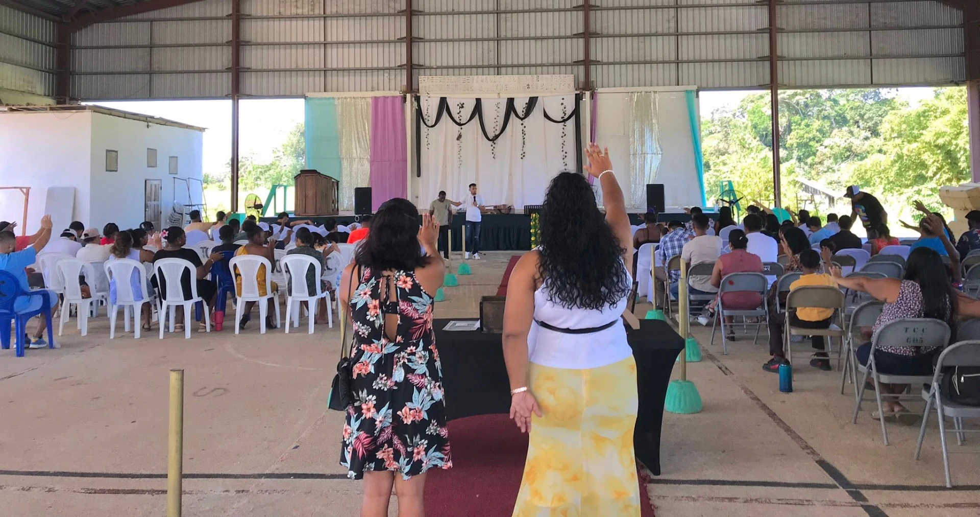 Congregation worshipping with hands raised under the church pavilion in Belize